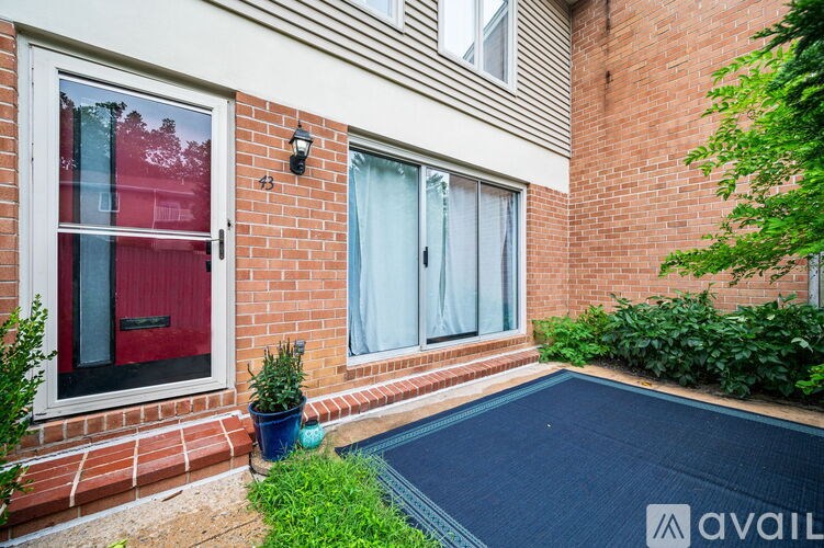 A brick house with a red door and a small pool in the backyard.