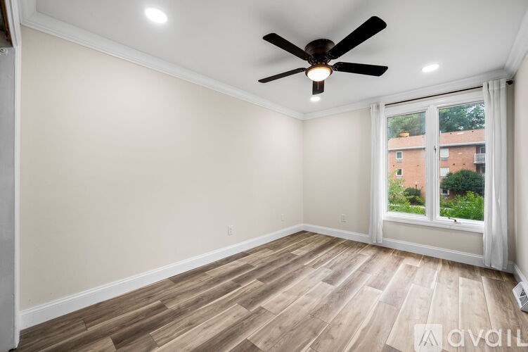 A room with a ceiling fan and wooden flooring.