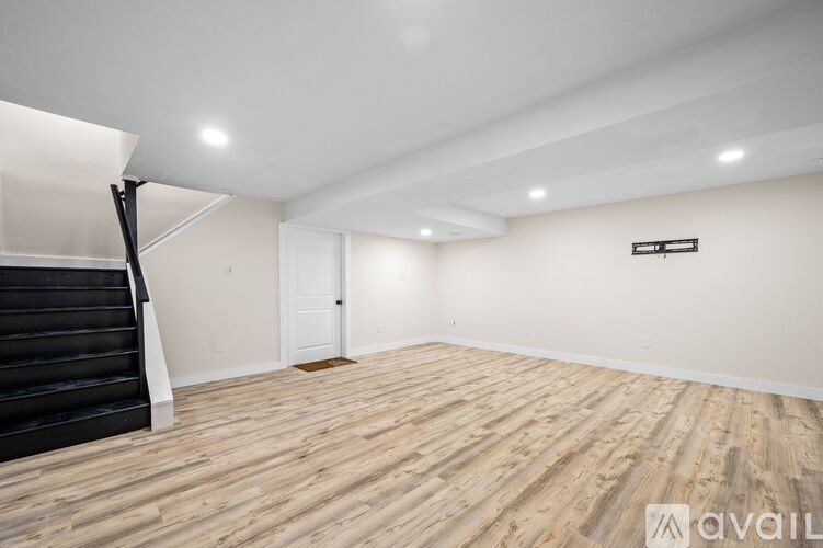A room with wooden flooring and a staircase on the left side.