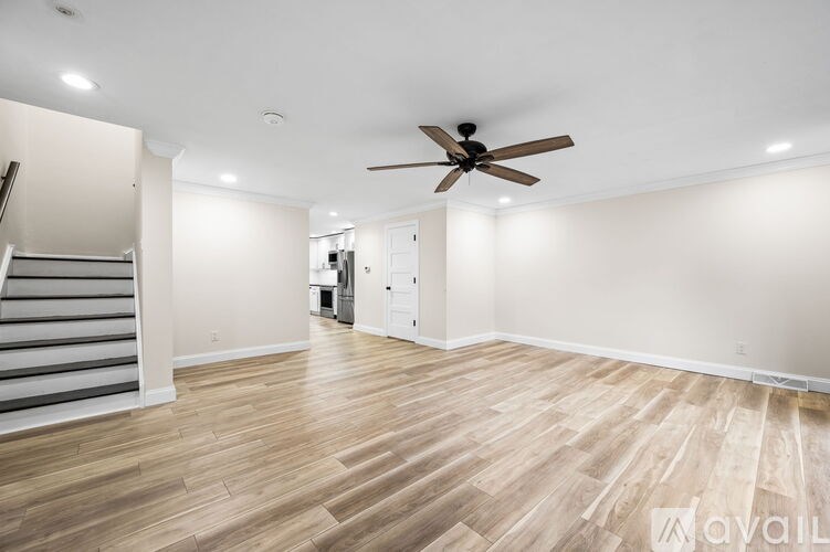 A spacious room with wooden flooring and a ceiling fan.