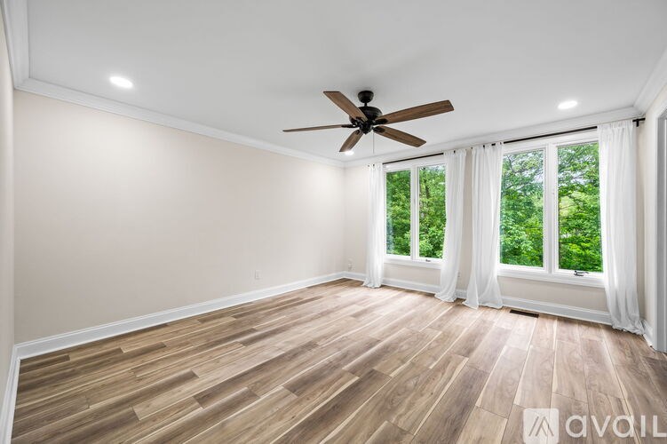A room with a ceiling fan and wooden flooring.