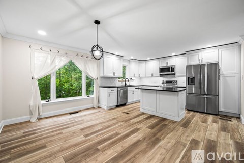A kitchen with white cabinets and a wooden floor.