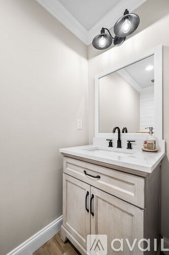 A bathroom vanity with a white countertop and a mirror above it.