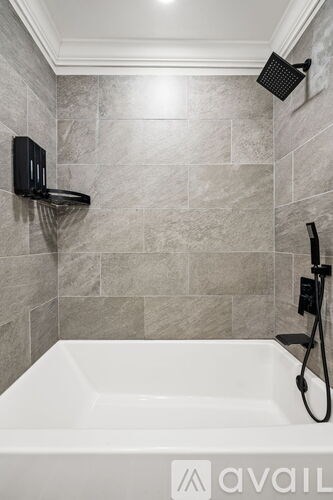 A bathroom with a white tub and grey tiles.
