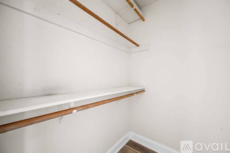 A white wall with a wooden shelf and a white ceiling with a brown line.