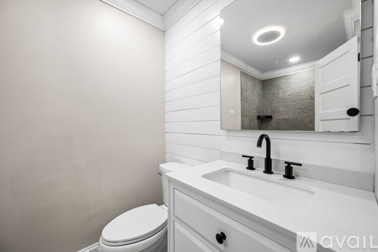 A white bathroom with a toilet, sink, and mirror.