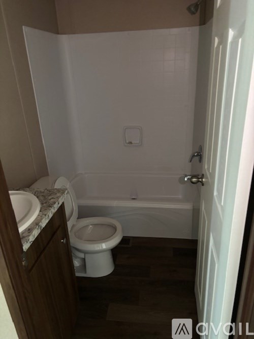 A white toilet sits in a bathroom next to a bathtub.