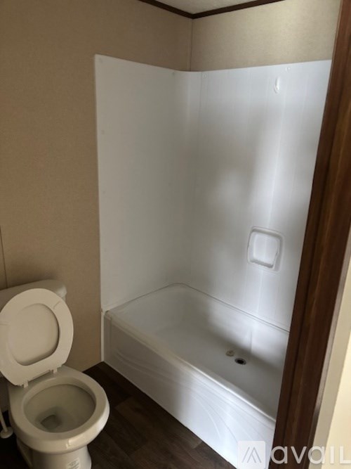 A white toilet sits next to a white bathtub in a small bathroom.