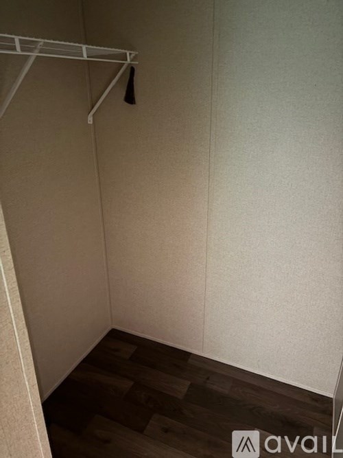 A small, empty room with a white wall and a wooden floor.