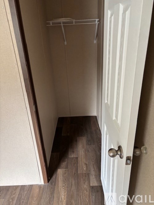 A small, empty closet with a white door and a wooden floor.