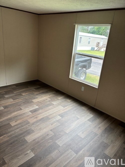 A room with a window showing a view of a house and a truck.