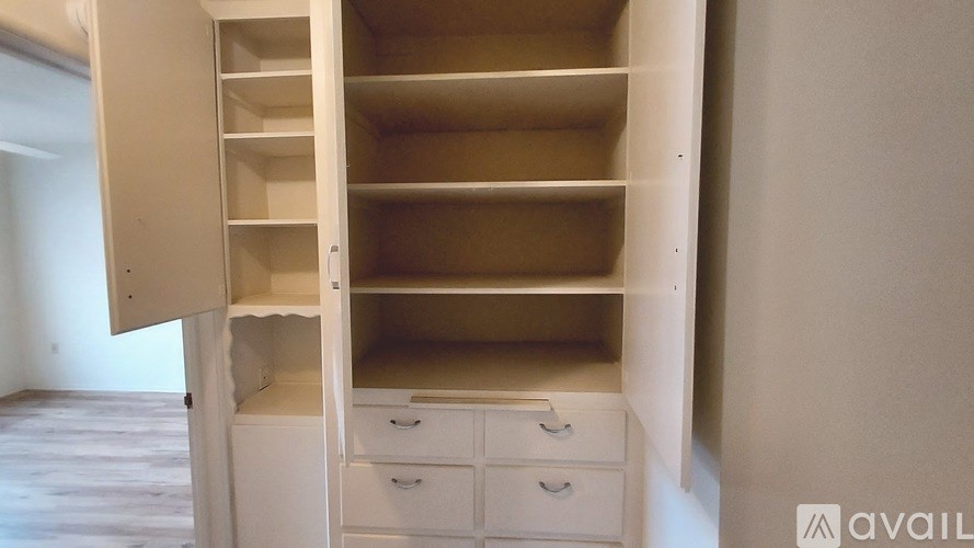 A white wardrobe with drawers is open, showing the empty shelves.