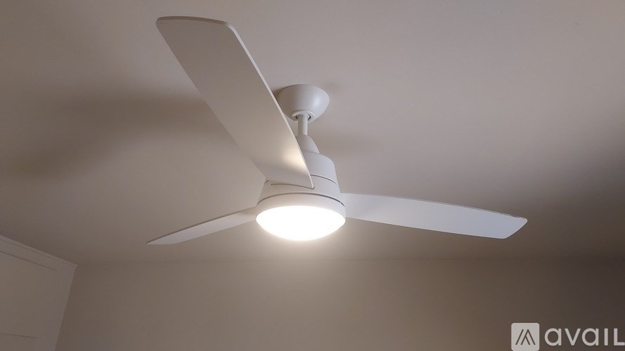 A white ceiling fan with a light on in a room.