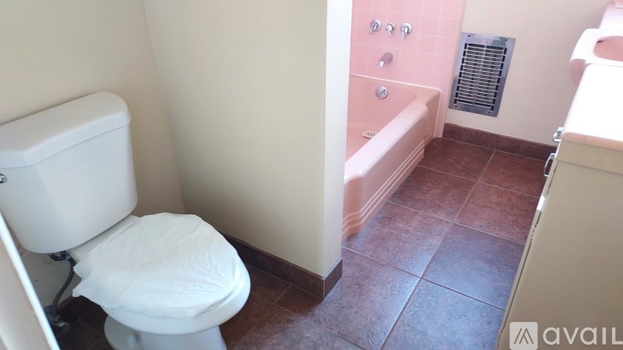 A white toilet in a bathroom with pink walls.