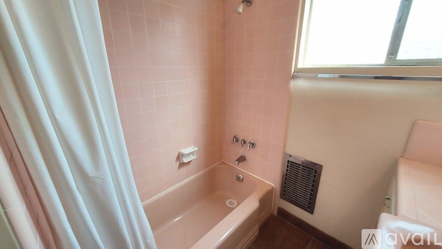 A bathroom with a pink tiled shower and a white bathtub.