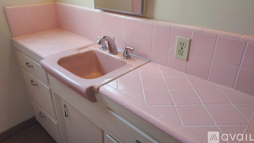 A bathroom with pink tiles and a window.