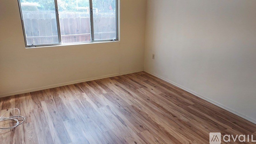 A room with wooden flooring and a window with blinds.