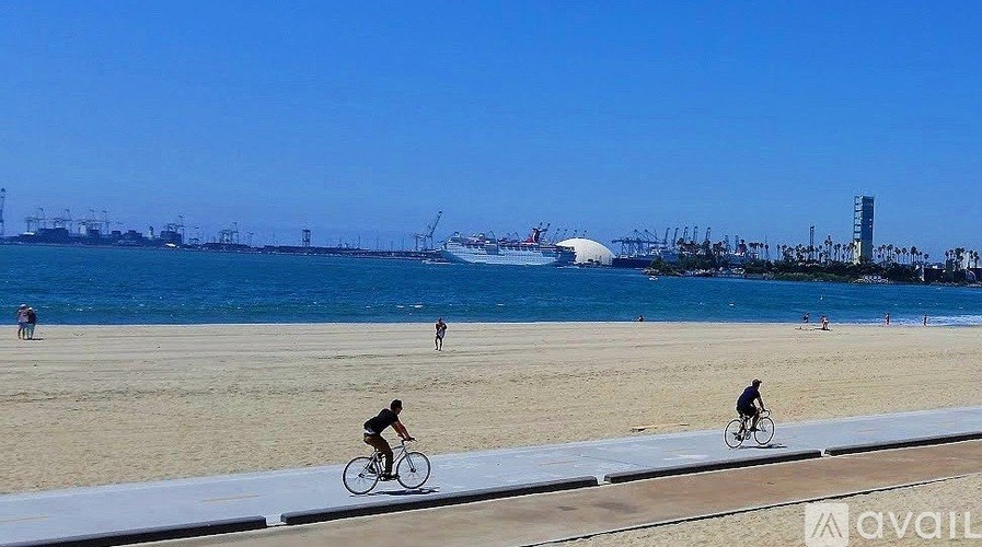 Two people riding bicycles on a beach with a clear blue sky.