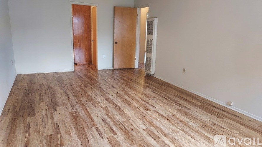 A room with wooden flooring and two doors.