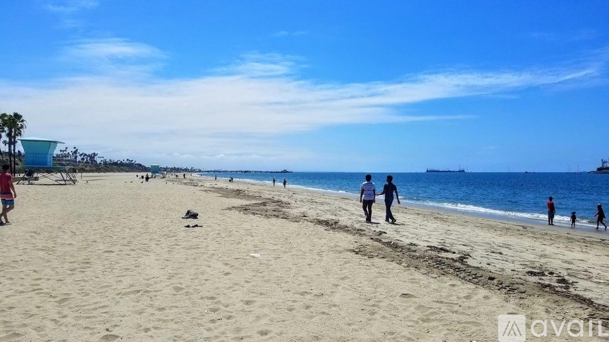 A beach scene with people walking and playing on the sand.