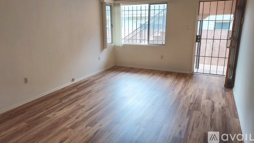 A room with wooden flooring and a window overlooking a balcony.