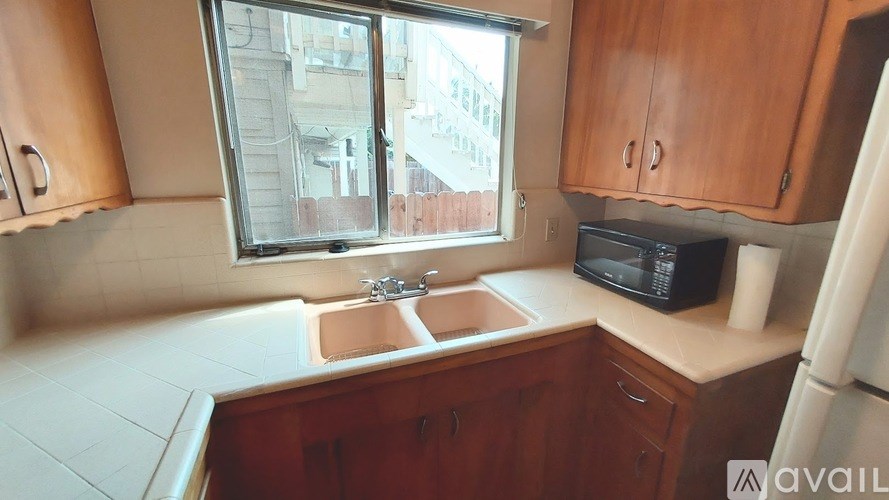 A kitchen with wooden cabinets and a window overlooking a building.
