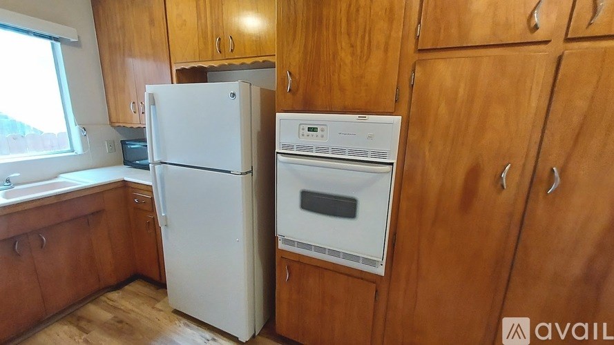 A white refrigerator and oven in a kitchen with wooden cabinets.
