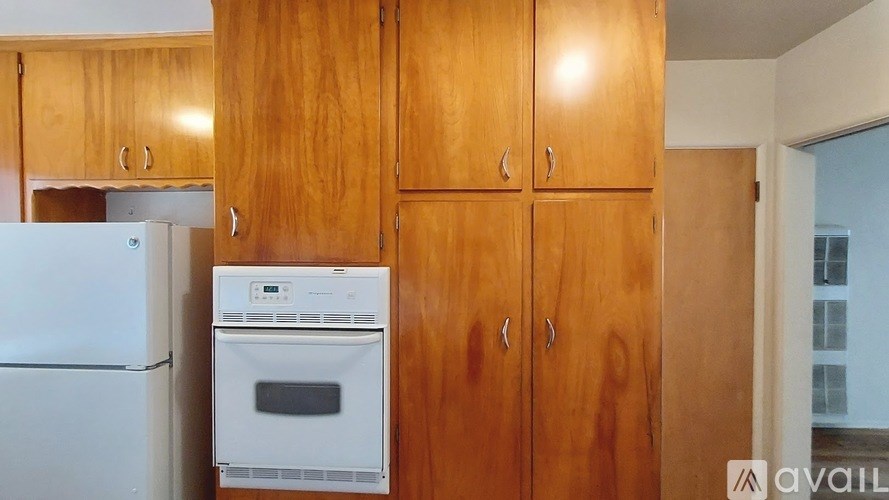 A kitchen with wooden cabinets and a white fridge.