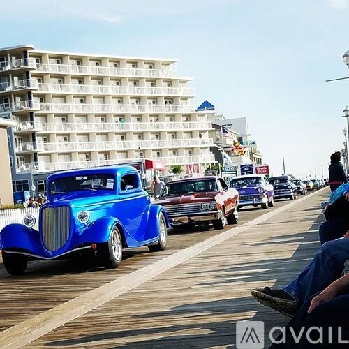A blue vintage car is parked on a boardwalk.