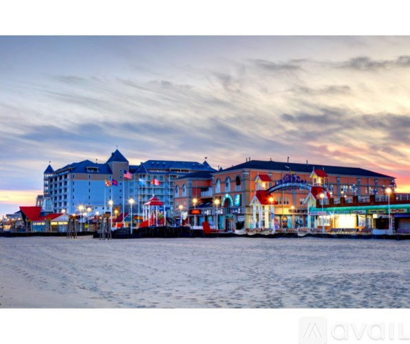 A large building with a red roof is lit up at dusk.