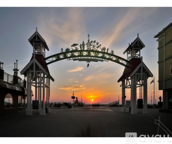 A roller coaster is in the foreground of a sunset at an amusement park.
