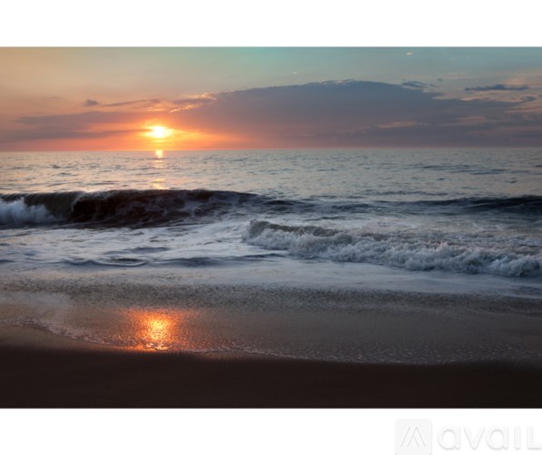 A sunset over the ocean with waves crashing on the shore.