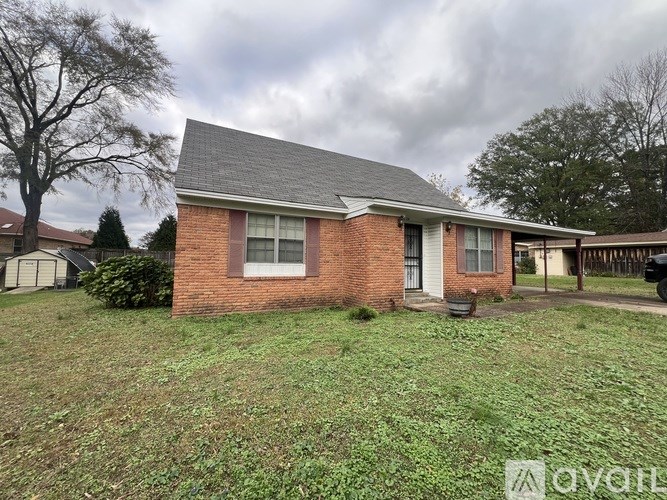A small brick house with a grey roof and a white window.