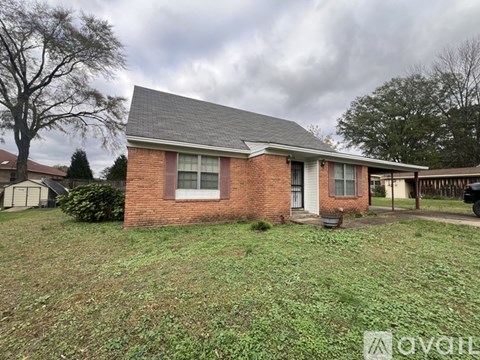 A small brick house with a grey roof and a white window.