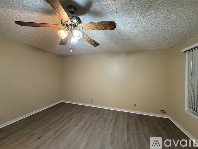 A room with a ceiling fan and wooden flooring.