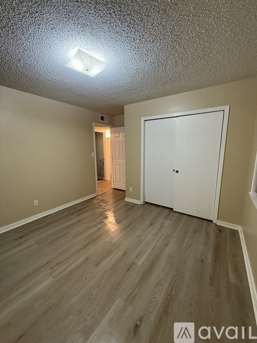 A room with a white door and wooden flooring.