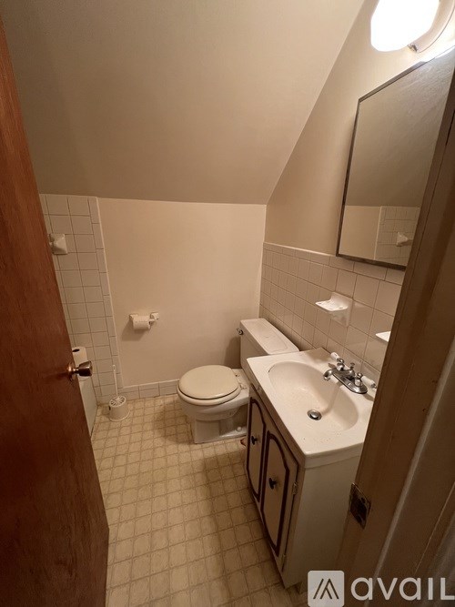 A bathroom with a toilet, sink, and mirror.