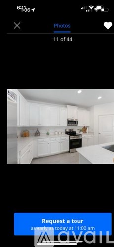 A kitchen with white cabinets and a blue button that says "Request a tour".