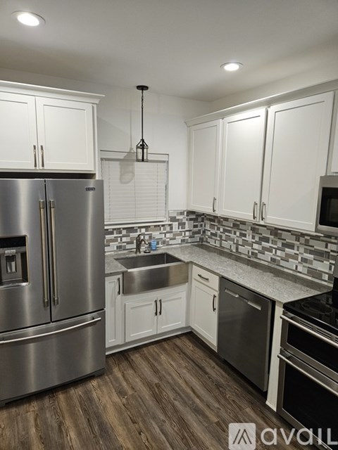 A kitchen with white cabinets and a stainless steel refrigerator.