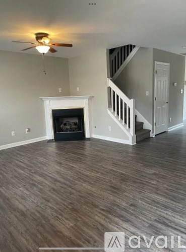 A living room with a fireplace and a staircase.