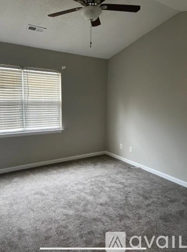 A room with a ceiling fan and a window with blinds.