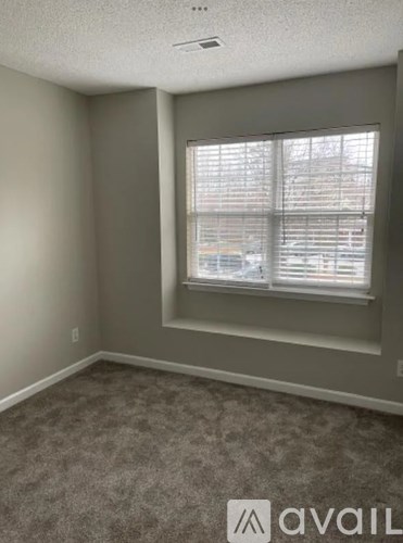 A room with a carpeted floor and a window with blinds.