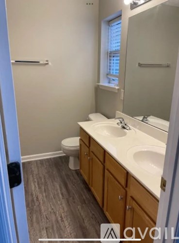 A bathroom with a toilet, sink and mirror.