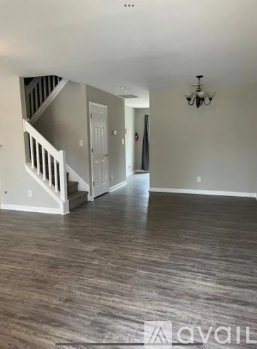 A spacious room with a staircase and a chandelier.