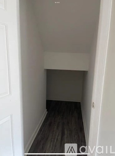A hallway with a wooden floor and white walls.