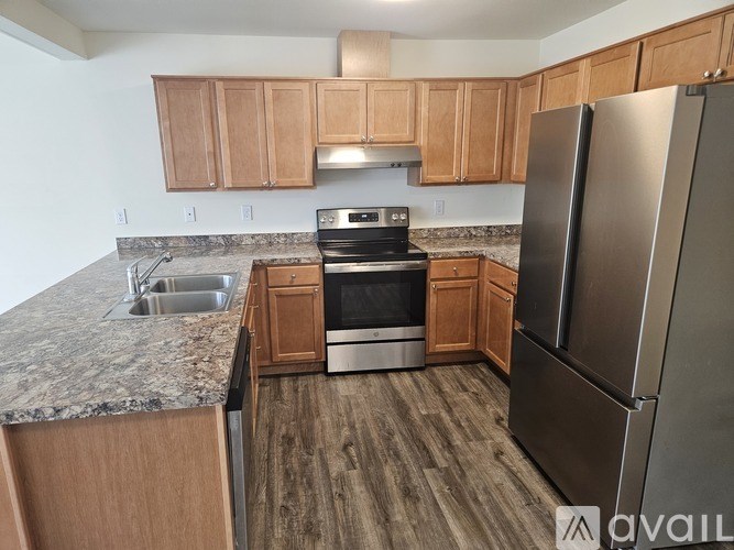 A kitchen with wooden cabinets and a stainless steel refrigerator.