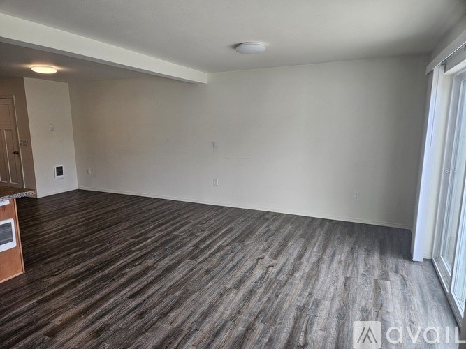A room with wooden flooring and a window on the right side.