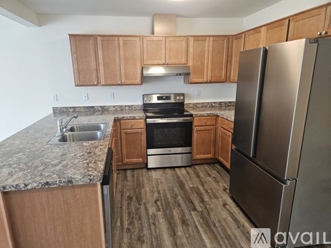 A kitchen with wooden cabinets and a stainless steel refrigerator.