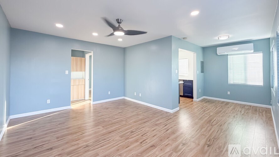 A spacious room with wooden flooring and a ceiling fan.