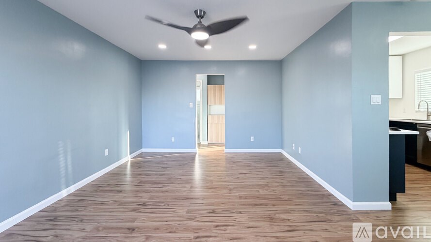 A spacious room with a ceiling fan and wooden flooring.